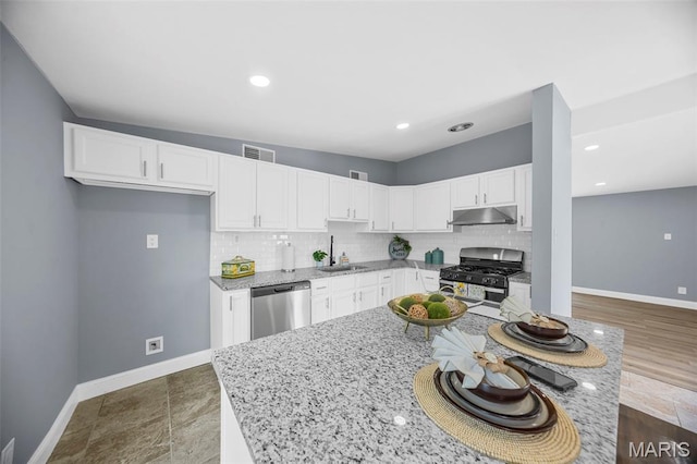 6822 Friarwood Dr, Saint Louis, MO 63134 - kitchen with stainless steel appliances, under cabinet range hood, light stone countertops, tasteful backsplash, and white cabinetry