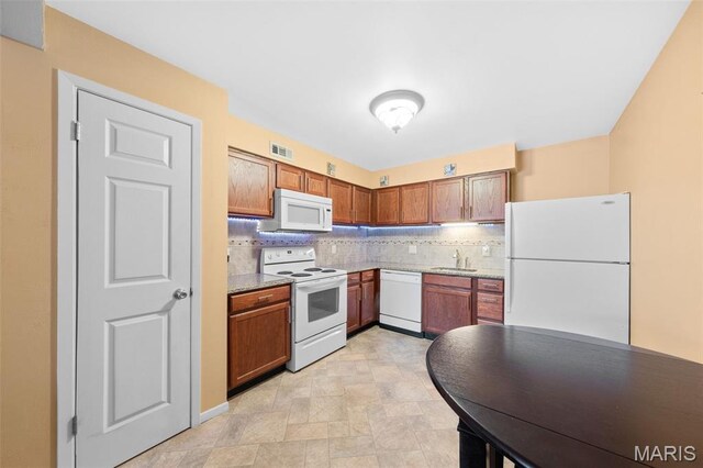 12114 Natural Bridge Rd Unit F, Bridgeton, MO 63044 - kitchen with white appliances, tasteful backsplash, brown cabinets, light countertops, and stone finish flooring