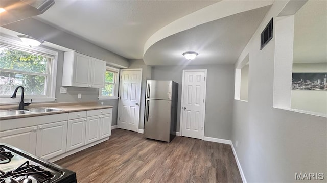 6613 Dunwold Dr, Saint Louis, MO 63134 - kitchen with freestanding refrigerator, dark wood-type flooring, gas range, white cabinets, and light countertops