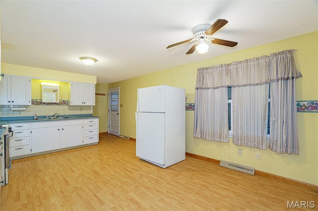 517 E 2nd St, Rolla, MO 65401 - kitchen with freestanding refrigerator, light wood-type flooring, ceiling fan, white cabinets, and tasteful backsplash