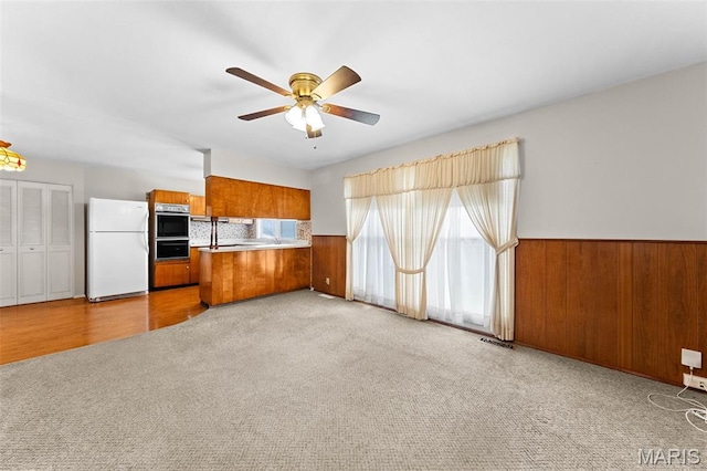 670 Gateswood Dr, Florissant, MO 63033 - kitchen featuring freestanding refrigerator, brown cabinetry, ceiling fan, carpet flooring, and a peninsula