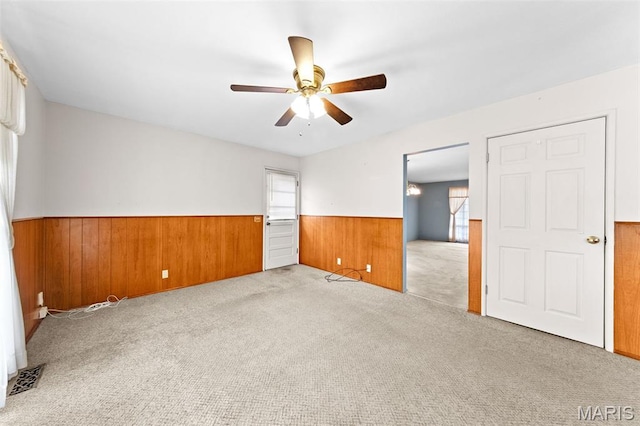 670 Gateswood Dr, Florissant, MO 63033 - carpeted empty room with a wainscoted wall, wooden walls, and a ceiling fan