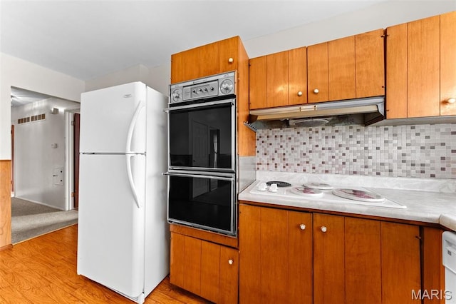 670 Gateswood Dr, Florissant, MO 63033 - kitchen with white appliances, light wood finished floors, light countertops, under cabinet range hood, and brown cabinetry