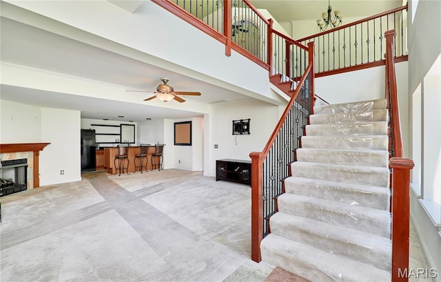 5 Tucker Manor Ct, Wentzville, MO 63385 - staircase featuring a high ceiling, a premium fireplace, a chandelier, carpet, and a ceiling fan