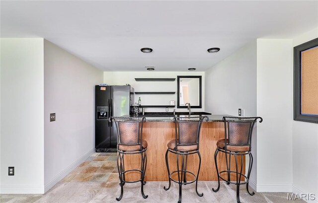 5 Tucker Manor Ct, Wentzville, MO 63385 - kitchen with black fridge with ice dispenser, a kitchen breakfast bar, and dark stone countertops