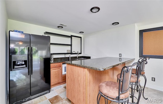 5 Tucker Manor Ct, Wentzville, MO 63385 - kitchen featuring black fridge with ice dispenser, a peninsula, a kitchen bar, and dark stone counters