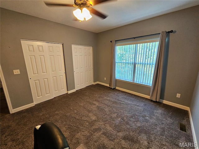 9339 Prairie Ridge Rd, Walsh, IL 62297 - unfurnished bedroom featuring multiple closets, dark colored carpet, and ceiling fan