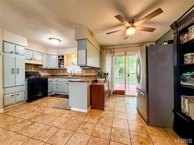 914 Ruby Dr, Farmington, MO 63640 - kitchen featuring black gas range, freestanding refrigerator, under cabinet range hood, dark countertops, and backsplash