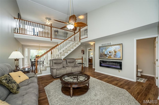 7202 Geneva Manor Ct, Oakville Township, MO 63129 - living room featuring wood finished floors, stairs, a towering ceiling, a chandelier, and a glass covered fireplace