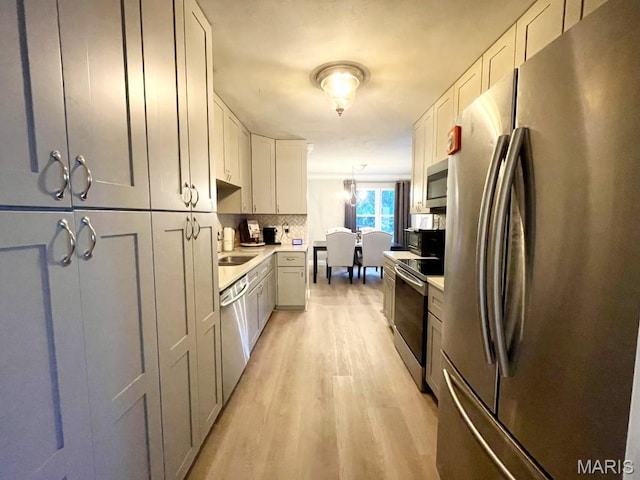 325 Fox Village Ct, Ballwin, MO 63021 - kitchen with stainless steel appliances, light wood-style flooring, light countertops, and tasteful backsplash