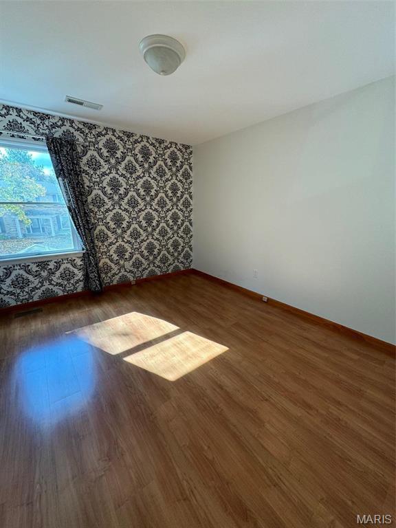 12383 Woodline Dr, Saint Louis, MO 63141 - empty room featuring wood finished floors and wallpapered walls