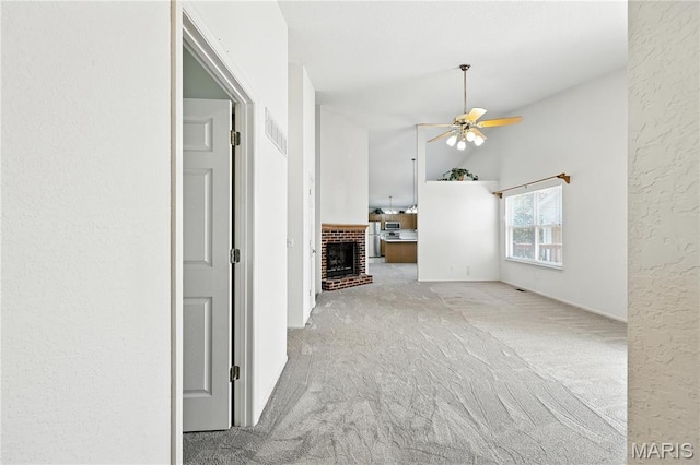 1516 Lienemann Dr Unit 26, Saint Charles, MO 63303 - unfurnished living room featuring a ceiling fan, carpet floors, a brick fireplace, vaulted ceiling, and a textured wall