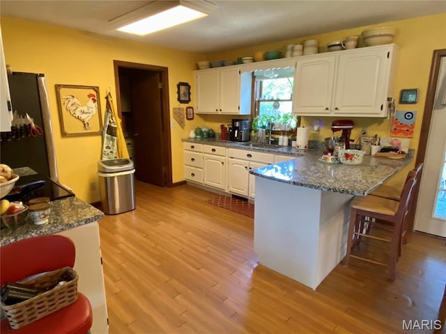 840 Delta Pine Ln, Sikeston, MO 63801 - kitchen featuring freestanding refrigerator, a peninsula, white cabinetry, and light wood-style floors