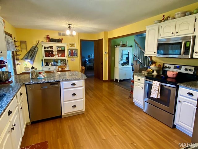 840 Delta Pine Ln, Sikeston, MO 63801 - kitchen with appliances with stainless steel finishes, white cabinetry, a peninsula, light wood-style flooring, and dark stone countertops