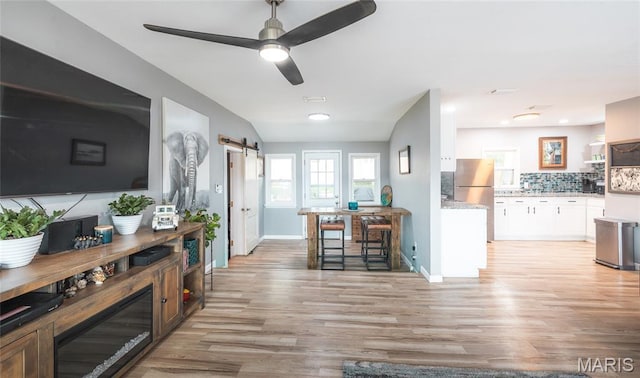 77 Indian Hills Dr, Cuba, MO 65453 - living area with light wood-type flooring, a barn door, a ceiling fan, and a desk