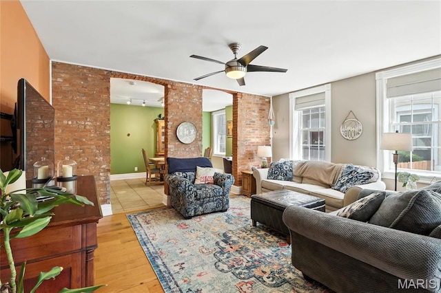 2812 Indiana Ave, Saint Louis, MO 63118 - living room with decorative columns, light wood finished floors, a ceiling fan, and brick wall