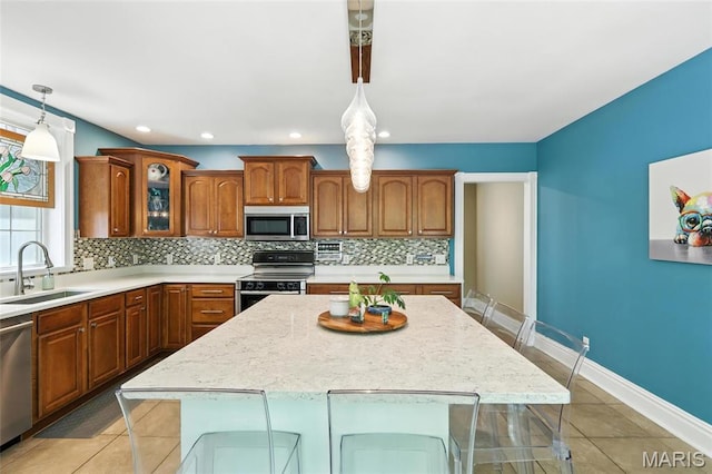 2812 Indiana Ave, Saint Louis, MO 63118 - kitchen featuring appliances with stainless steel finishes, backsplash, brown cabinetry, a center island, and glass insert cabinets