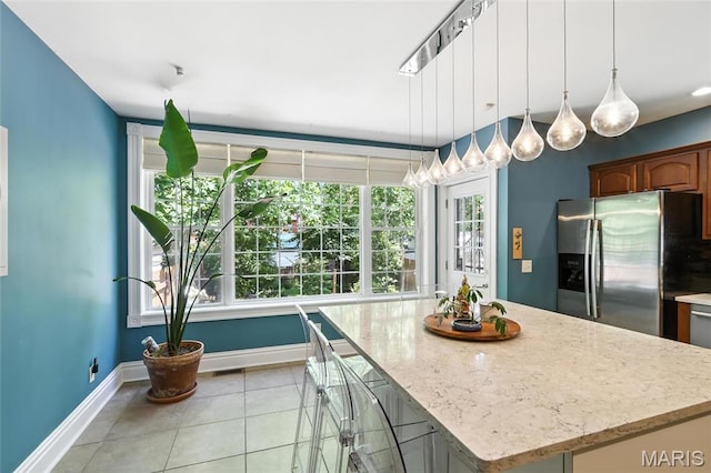 2812 Indiana Ave, Saint Louis, MO 63118 - kitchen featuring stainless steel fridge with ice dispenser, light tile patterned flooring, a kitchen island, light stone counters, and pendant lighting