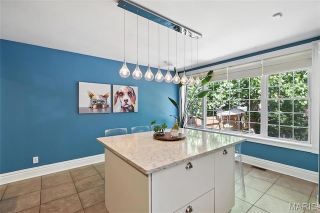 2812 Indiana Ave, Saint Louis, MO 63118 - kitchen featuring tile patterned flooring, a center island, pendant lighting, light stone countertops, and white cabinets