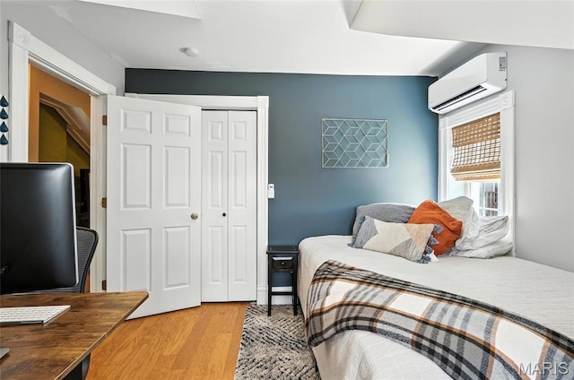 2812 Indiana Ave, Saint Louis, MO 63118 - bedroom with an AC wall unit, a closet, light wood-type flooring, and an office area