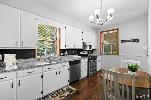 512 N Hills Dr, Saint Louis, MO 63121 - kitchen featuring stainless steel appliances, a chandelier, wainscoting, white cabinets, and decorative backsplash