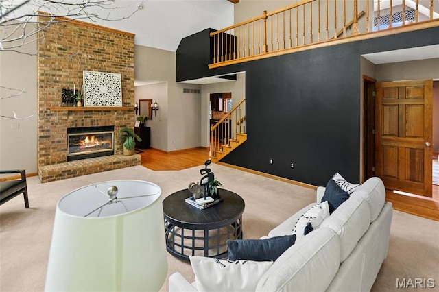 4775 S Hazel Rd, Edwardsville, IL 62025 - living room with a high ceiling, stairway, carpet, a brick fireplace, and wood finished floors