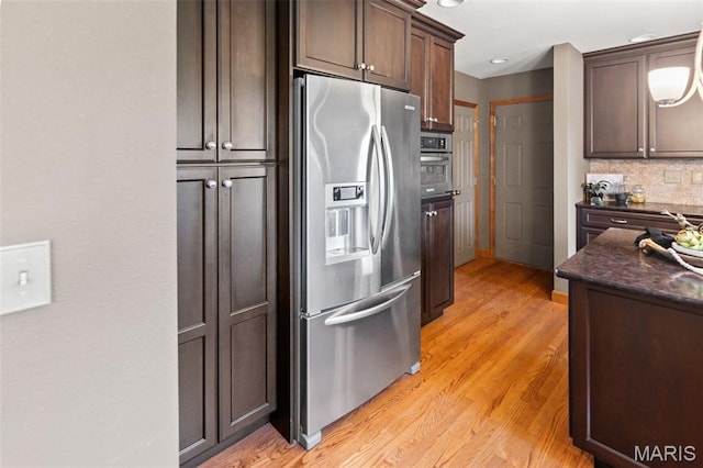 4775 S Hazel Rd, Edwardsville, IL 62025 - kitchen with stainless steel appliances, dark brown cabinetry, light wood-style flooring, decorative backsplash, and dark stone countertops