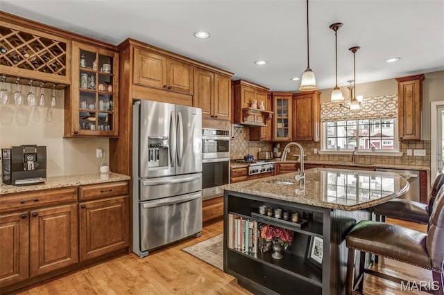 1029 Brownell Ave, Glendale, MO 63122 - kitchen featuring appliances with stainless steel finishes, brown cabinetry, a kitchen bar, light stone counters, and decorative backsplash