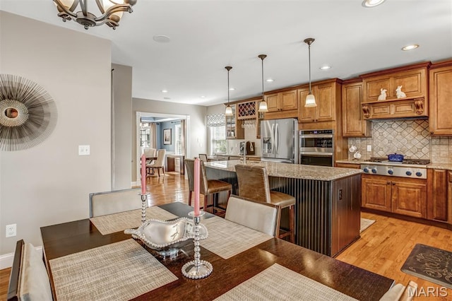 1029 Brownell Ave, Glendale, MO 63122 - kitchen featuring stainless steel appliances, light wood-style floors, a center island with sink, brown cabinets, and recessed lighting
