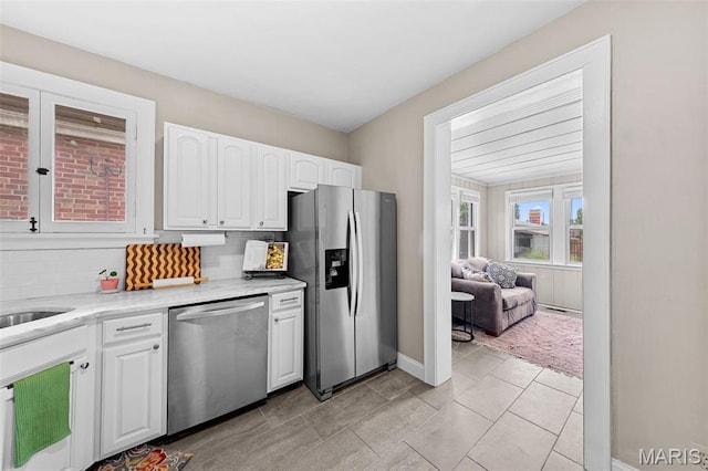 6016 Scanlan Ave, Saint Louis, MO 63139 - kitchen featuring appliances with stainless steel finishes, white cabinetry, backsplash, light stone counters, and light tile patterned floors