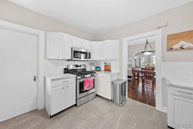 6016 Scanlan Ave, Saint Louis, MO 63139 - kitchen featuring appliances with stainless steel finishes, white cabinetry, tasteful backsplash, and light stone countertops