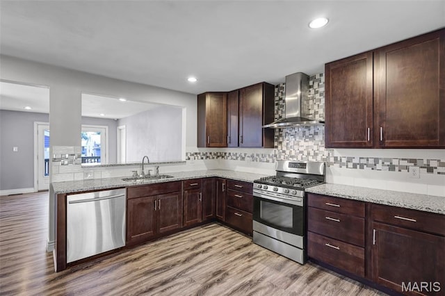 7104 Leona St, Saint Louis, MO 63116 - kitchen with wall chimney range hood, stainless steel appliances, light wood-style flooring, decorative backsplash, and light stone countertops