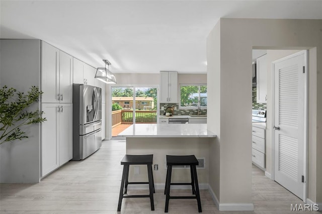 383 Messina Dr, Ballwin, MO 63021 - kitchen featuring appliances with stainless steel finishes, light countertops, a kitchen breakfast bar, light wood-style floors, and a peninsula