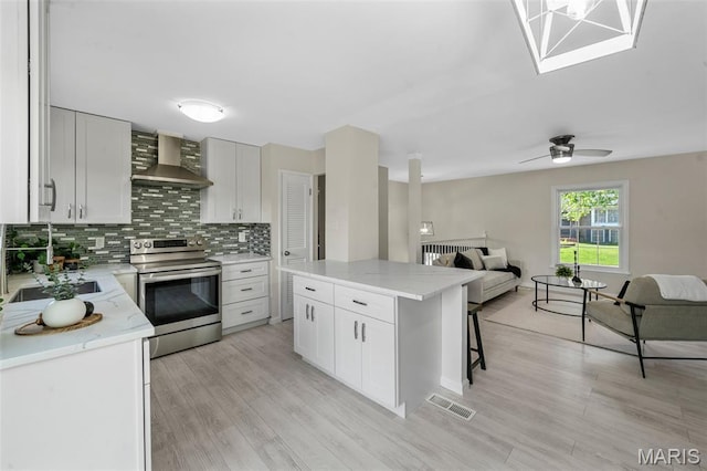 383 Messina Dr, Ballwin, MO 63021 - kitchen featuring wall chimney range hood, stainless steel electric stove, open floor plan, backsplash, and light wood-style flooring