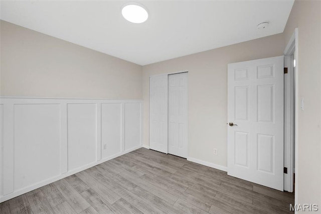 383 Messina Dr, Ballwin, MO 63021 - unfurnished bedroom featuring wood finished floors, a decorative wall, a closet, and wainscoting