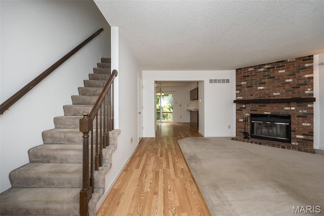 2266 Highland Hill Dr Unit F, Saint Peters, MO 63376 - stairway with wood finished floors, a textured ceiling, and a brick fireplace