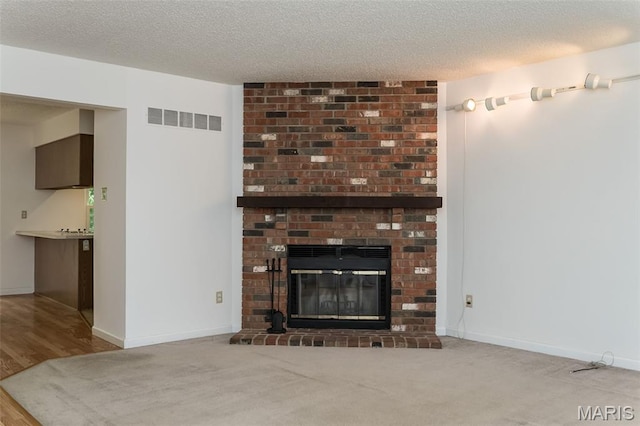 2266 Highland Hill Dr Unit F, Saint Peters, MO 63376 - unfurnished living room featuring a fireplace, a textured ceiling, and wood finished floors