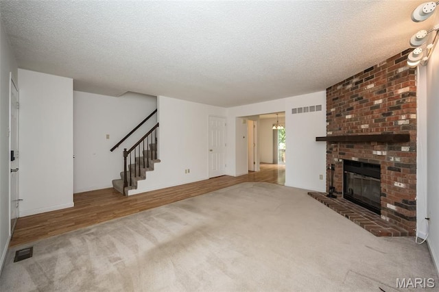 2266 Highland Hill Dr Unit F, Saint Peters, MO 63376 - unfurnished living room featuring carpet, stairs, a textured ceiling, a brick fireplace, and a chandelier