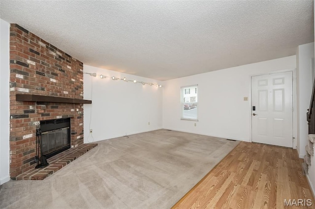 2266 Highland Hill Dr Unit F, Saint Peters, MO 63376 - unfurnished living room featuring a textured ceiling, a brick fireplace, and wood finished floors