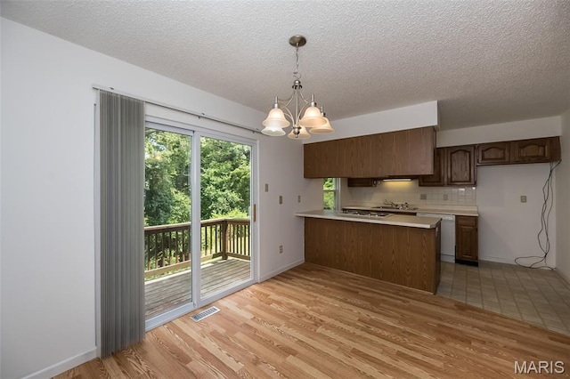 2266 Highland Hill Dr Unit F, Saint Peters, MO 63376 - kitchen featuring a peninsula, light countertops, a chandelier, dishwasher, and light wood-style floors