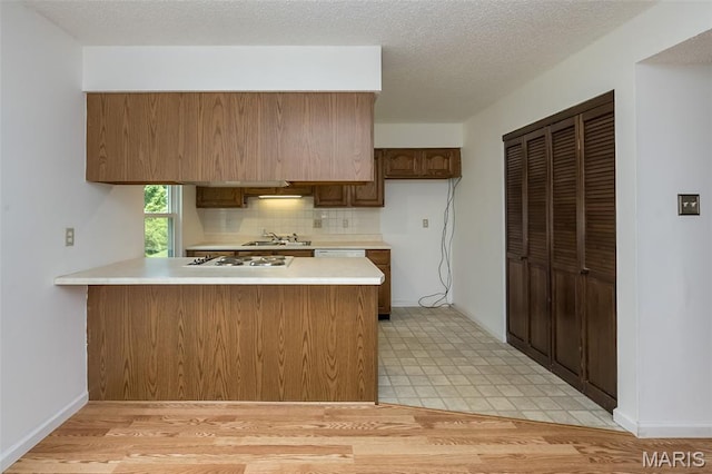 2266 Highland Hill Dr Unit F, Saint Peters, MO 63376 - kitchen featuring a peninsula, light countertops, decorative backsplash, white gas cooktop, and a textured ceiling