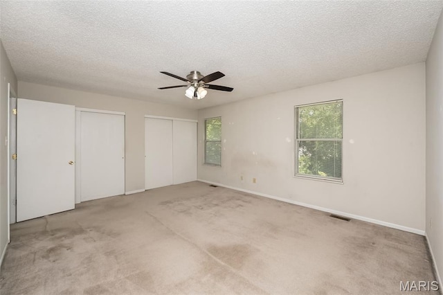 2266 Highland Hill Dr Unit F, Saint Peters, MO 63376 - unfurnished bedroom with two closets, multiple windows, carpet floors, and a textured ceiling