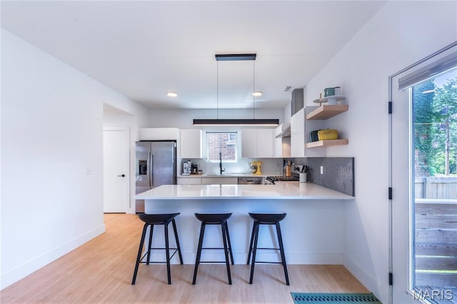 4133 Lafayette Ave, Saint Louis, MO 63110 - kitchen featuring stainless steel fridge with ice dispenser, a peninsula, light countertops, white cabinets, and light wood-style floors