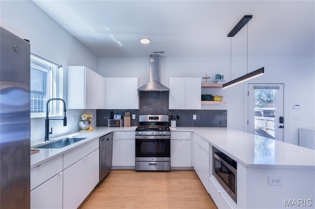 4133 Lafayette Ave, Saint Louis, MO 63110 - kitchen featuring wall chimney exhaust hood, stainless steel appliances, open shelves, a peninsula, and white cabinets