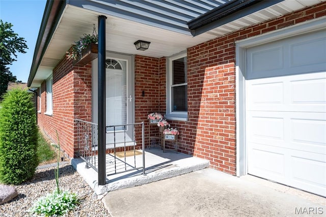 doorway to property with an attached garage, brick siding, and covered porch