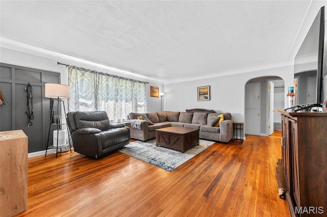 living area featuring arched walkways, wood finished floors, and a textured ceiling