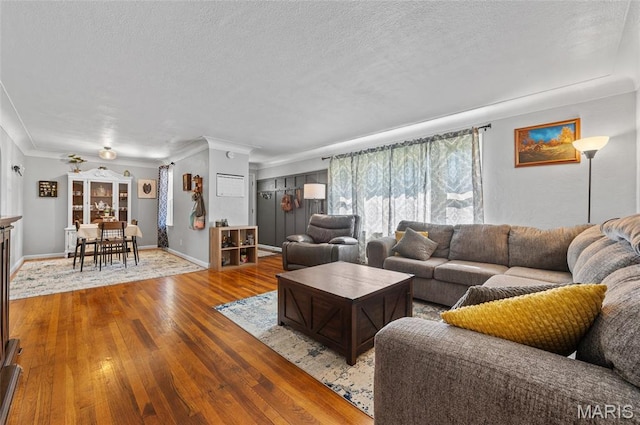 living room with wood-type flooring, a textured ceiling, and ornamental molding
