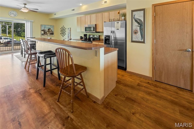 319 Timber Ridge Dr, Grafton, IL 62037 - kitchen with appliances with stainless steel finishes, a breakfast bar, a ceiling fan, dark wood-type flooring, and light brown cabinetry