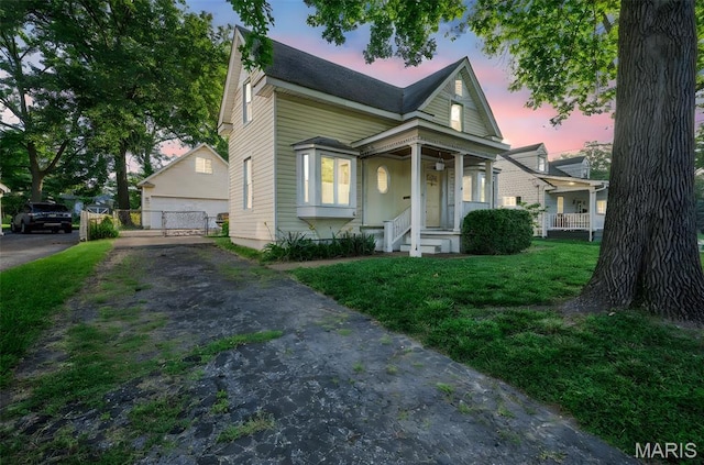 135 Oak Tree Dr, Webster Groves, MO 63119 - view of front facade featuring covered porch, a detached garage, an outbuilding, and a front lawn