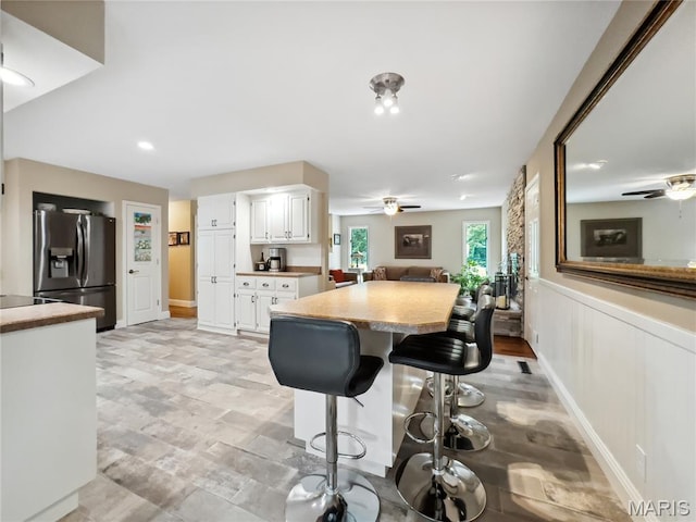 1171 Thunder Mountain Rd, Camdenton, MO 65020 - kitchen featuring stainless steel refrigerator with ice dispenser, a ceiling fan, light countertops, white cabinetry, and a kitchen bar